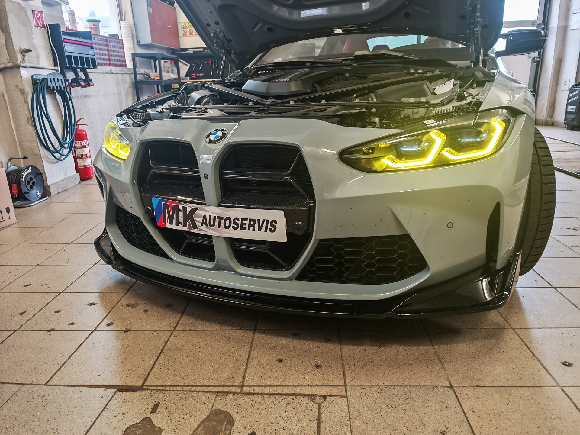 Sivi BMW M3 prednji dio u radionici s podignutom haubicom